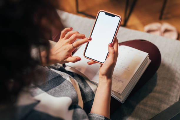 Anonymous Woman Using her Mobile Phone at Home (Blank Screen, Copy Space) Hands of an unrecognizble woman using a smartphone, a close up. looking at cell phone screen stock pictures, royalty-free photos & images