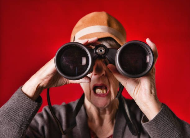 istock Senior woman looking intently through pair of binoculars 1295659057