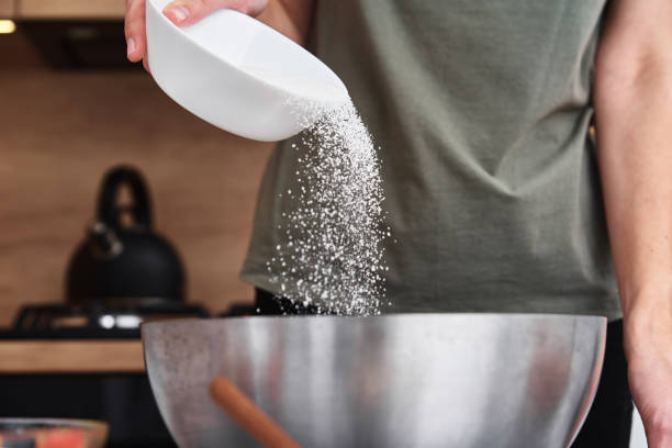 istock Woman in kitchen cooking a dough. Hands pour flour into a bowl 1295659455