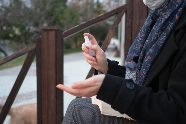 istock Woman using a hand sanitizer on the park. 1295659581