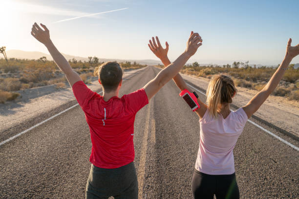 istock Man and woman stretching before running on empty road 1295662105