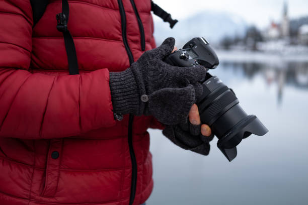 istock Photographer checking camera settings wearing mittens. 1295664460