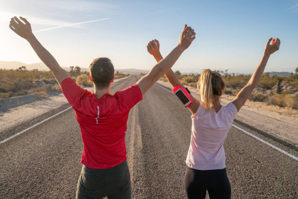 istock Man and woman stretching before running on empty road 1295666033