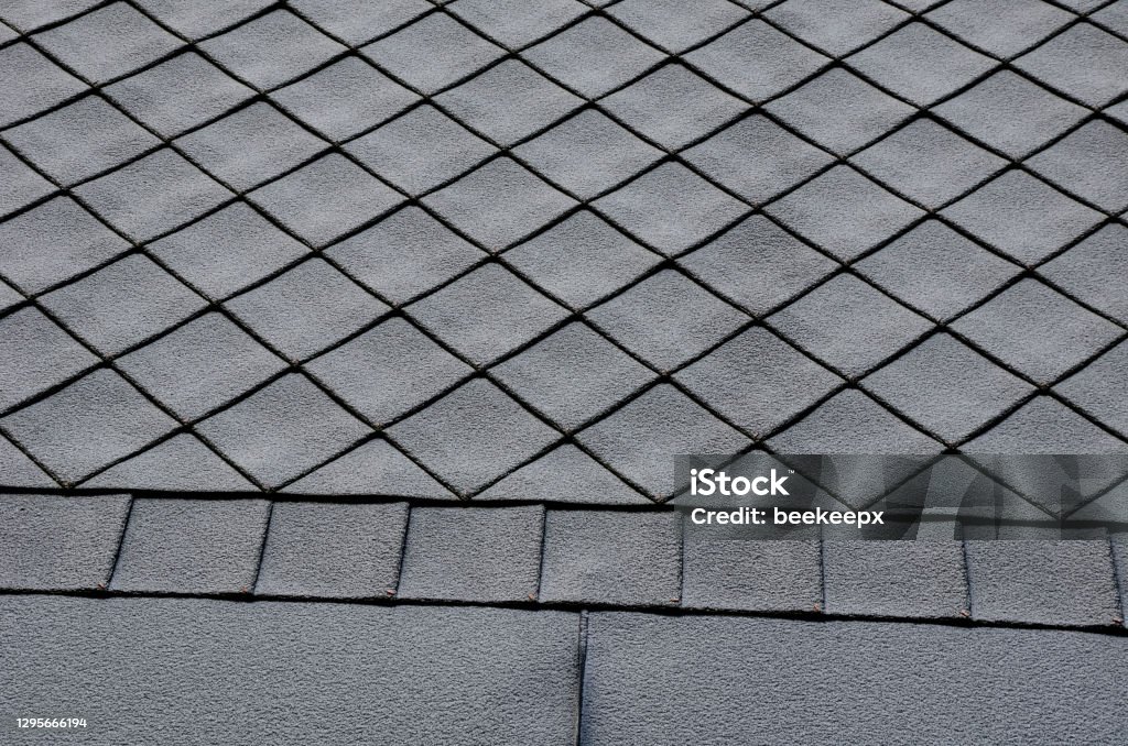 gray roof tiles with windows square slate template. laid obliquely. square grid pattern. the lower edge of the roof is formed by a metal strip for framing and better tearing off a layer of snow. ancient, architecture, artificial, background, cement, construction, cottage, design, detail, diagonal, edge, framing, frosted, gray, historical, hole, house, icing, imitate, imitation, material, mountain, oblique, pattern, plastic, reconstruction, rectangle, recycling, renew, roof, roofer, roofing, row, saddle, shape, slate, snow, surface, technology, template, texture, textured, tile, tiles, tin, ventilation, waste, white, window, windows Rooftop Stock Photo