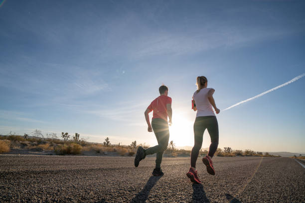 istock Low angle view of two runners on empty highway at sunrise 1295666317