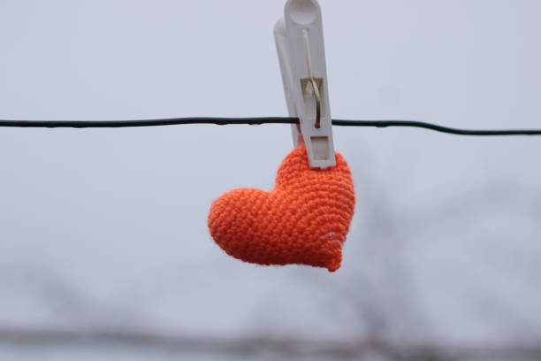 Knitted heart to dry on a clothespin. Break in a love relationship. stock photo