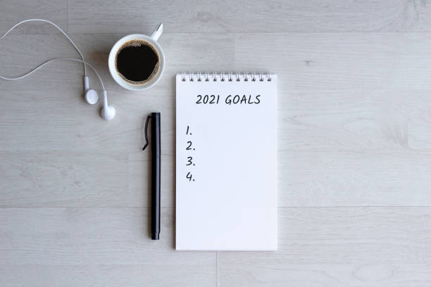 istock 2021 Goals Checklist. Top view word goals on notebook with pen and coffee. new year resolutions and plan. 1295668362