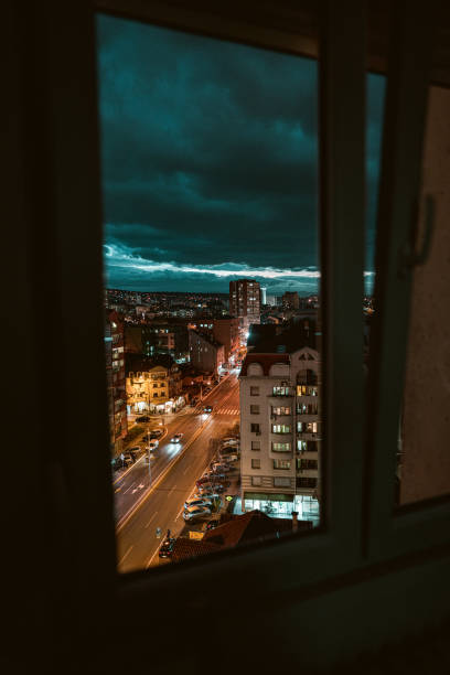 Cityscape and cloudy sky through window of skyscraper at night