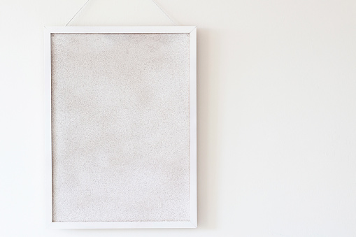 empty white cork board hanging on the wall. horizontal copy space