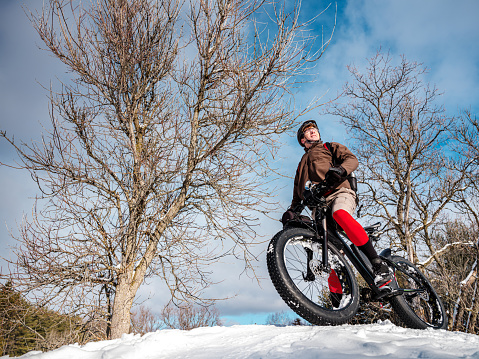 Adult man riding fat bicycle in winter. Outdoor conservation area of Southern Ontario, Canada in January,