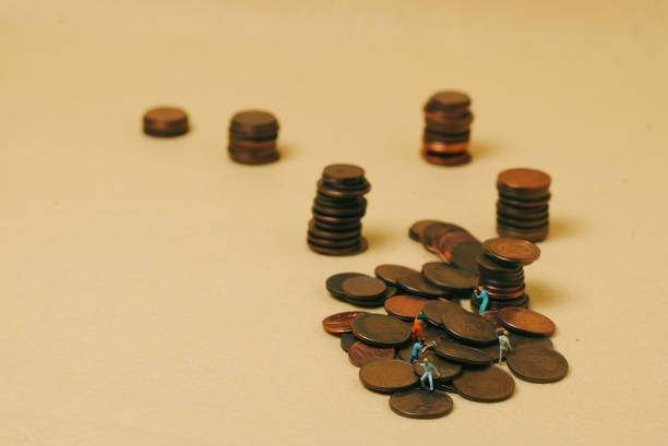 istock economy and work: miniature workers on coins with a yellow background 1295672622
