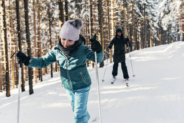 little girl on ski with family in the sunny snowy forrest frontal  view on little girl on ski with her mother behind in snowy landscape in the Giant Mountains karkonosze mountain range photos stock pictures, royalty-free photos & images