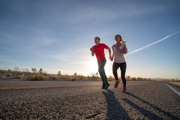 istock Low angle view of two runners on empty highway at sunrise 1295675101