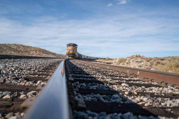 12/12/2018 Joshua national preserve, California, USAA yellow locomotive train arriving from desert landscape, it carries cargo containers.