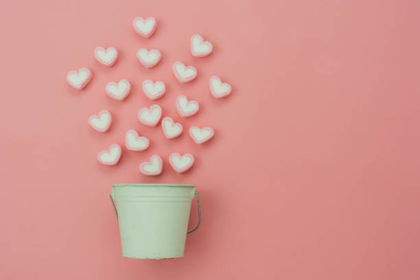 istock Table top view aerial image of sign valentine's day background concept.Flat lay arrangement white coffee cup with steam heart shape on modern pink paper at home office desk studio.Pastel tone design. 1295678122