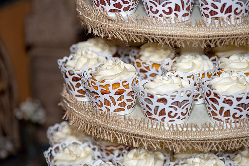 Assorted cupcakes in fancy cups with vanilla frosting  on cake tower wedding cake