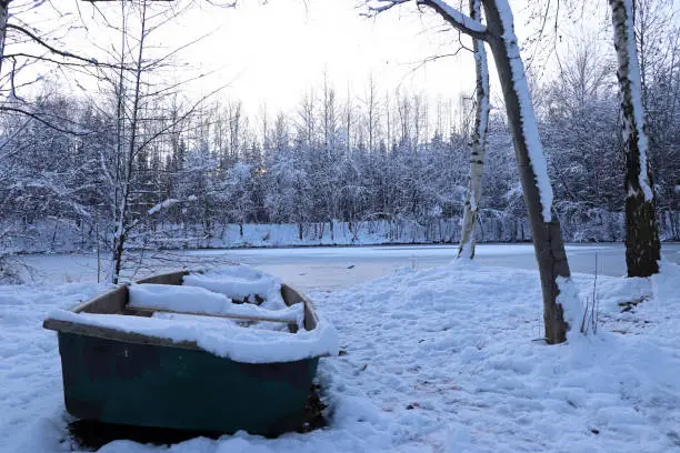 old boat at the frozen pond in the snow