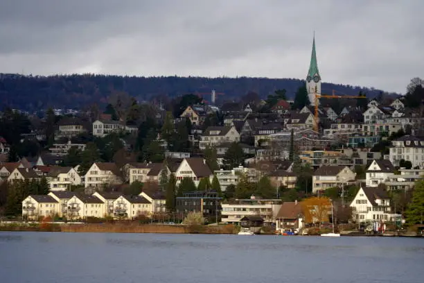 Panoramic view on village Zollikon on the bank of Lake Zurich in Switzerland. Photo taken from the lake that is in the foreground.