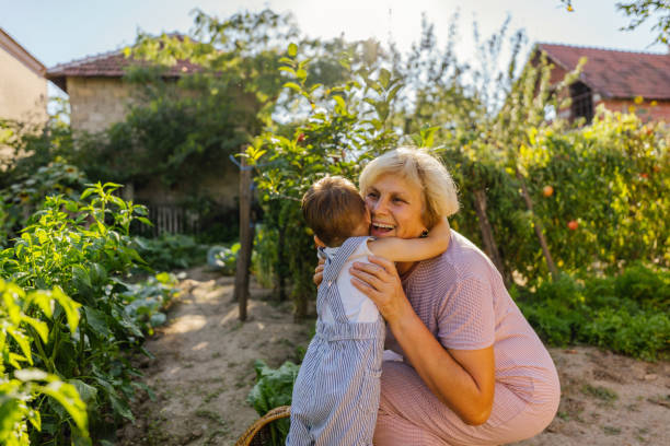 Grandma, you're the best! Photo of a little boy hugging his grandmother while picking homegrown, fresh vegetables in a home organic garden. grandson photos stock pictures, royalty-free photos & images