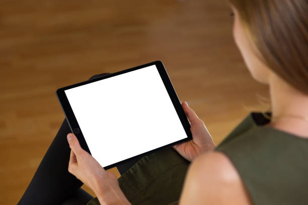 istock Woman sitting and holding tablet with blank white screen in her hands. 1295681753