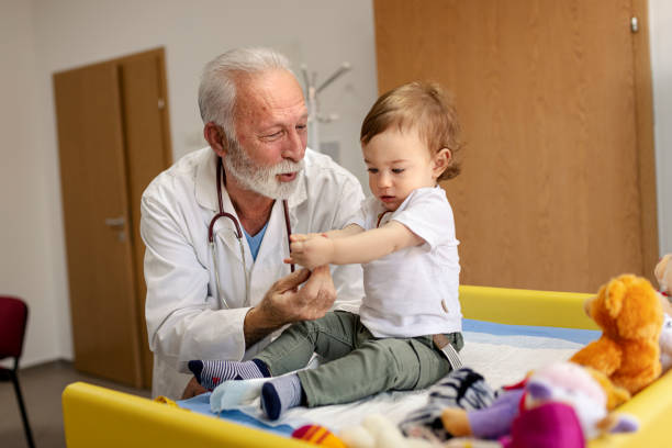 istock Doctor playing with baby boy on the table in doctors office 1295684020