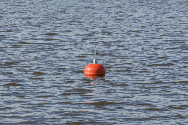 a red floating buoy swinging on the waves of the river, denoting a deep place