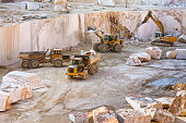Construction vehicles working in marble quarry with oversized marble blocks