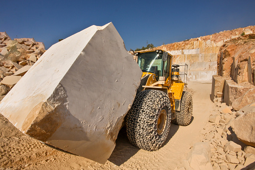 A big loader (Bulldozer) carrying an oversized marble block