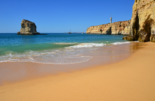 Ferragudo, Lagoa, Algarve / Faro District, Portugal: sand and cliffs at Caneiros Beach - in the background the Altar Headland and the Gaivotas Islet - Praia dos Caneiros, Ponta do Altar e Leixão das Gaivotas.