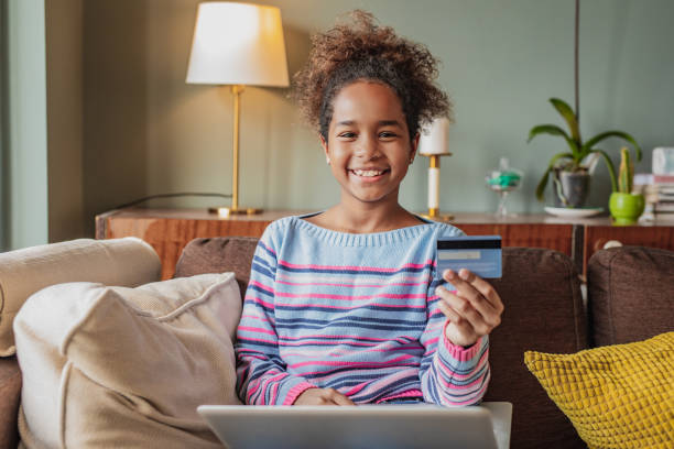 little girl is using credit card for e commerce at home - paying children only retail childhood imagens e fotografias de stock