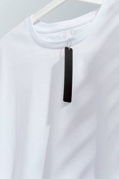 istock White t-shirt with blank black price tag, displayed on white hanger 1295688598