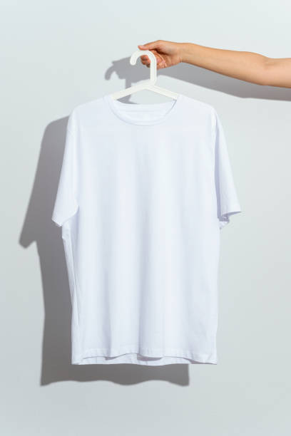 istock Hand holding white t-shirt mockup, template on white hanger 1295691582