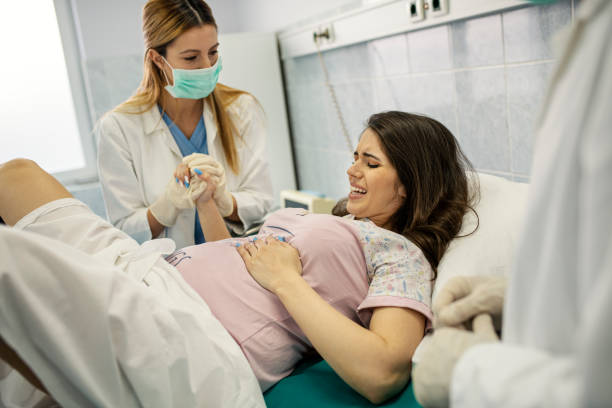 In the Hospital Nurse Giving Birth Support, Obstetricians Assisting. Modern Delivery Ward with Professional Midwives In the Hospital Nurse Giving Birth Support, Obstetricians Assisting. Modern Delivery Ward with Professional Midwives childbirth photos stock pictures, royalty-free photos & images