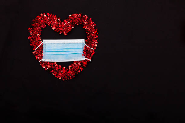 istock A red heart with mask with black background 1295692986