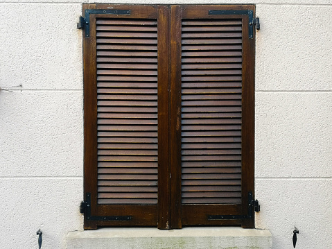 Sky blue colored wooden window with the opening shutters on brick wall