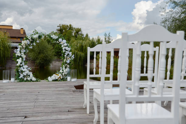 istock Place for wedding ceremony outdoors, copy space. Circle wedding arch decorated with flowers and chairs on each side of archway. Wedding setting 1295694865