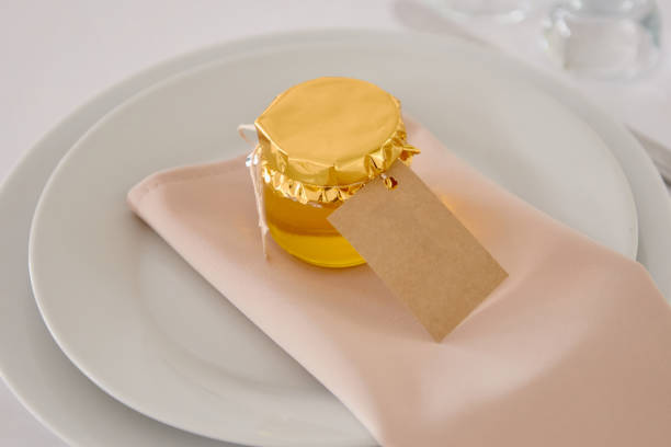 Table set with blank guest card, plate with napkin and honey, copy space. Place setting at wedding reception in restaurant