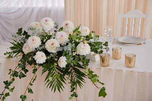 Lush floral arrangement of white chrysanthemum flowers on table. Luxury wedding decorations. Wedding presidium in restaurant, copy space. Banquet table for newlyweds