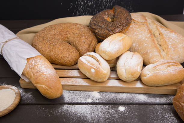 padaria - pães crocantes rústicos dourados de pão e pães na vista de fundo do lousa preto - baked bread breakfast brown - fotografias e filmes do acervo