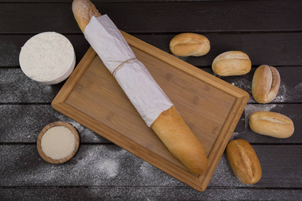 bakery - gold rustic crusty loaves of bread and buns on black chalkboard background top view - baked bread breakfast brown imagens e fotografias de stock