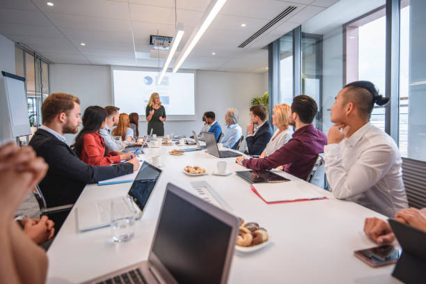 istock Female Executive Giving Presentation to Management Team 1295701119