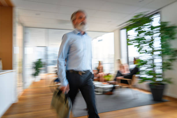 istock Casual Executive with Briefcase Walking Through Office Lobby 1295701142