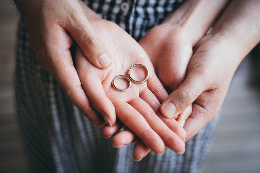 Close-Up Of Couple Holding Hands and showing off their wedding rings