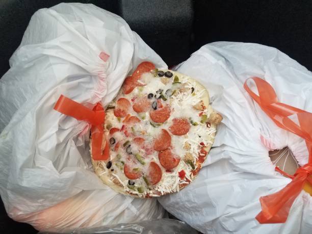 frozen pizza with pepperoni in garbage can with trash bags