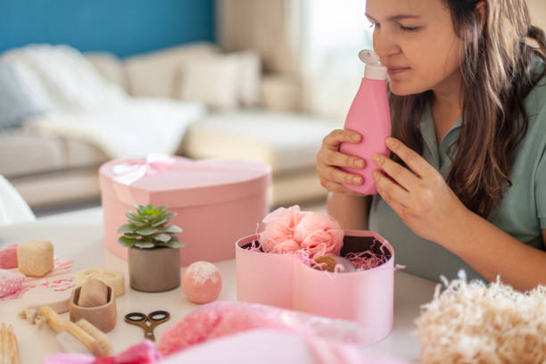 istock Young woman smelling opened shampoo jar from heart shaped gift box set with cosmetic bath supplies 1295721507