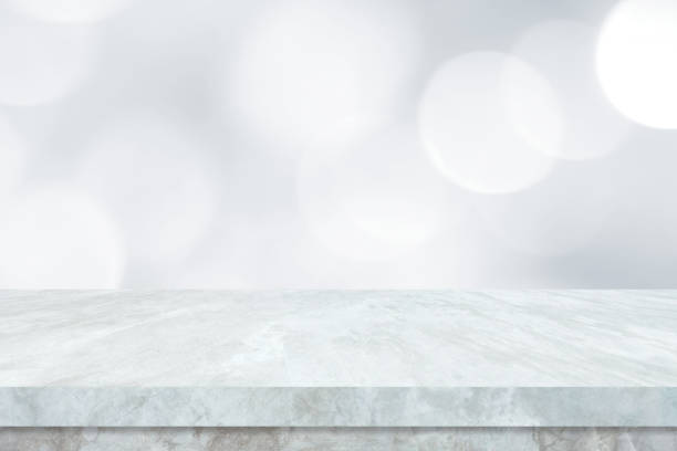 istock Empty white table top, counter, desk over blur perspective store with bokeh light background, White marble stone table, shelf and blurred shop for food, product display mockup, template, banner 1295722387