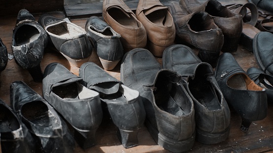 A pile of black and brown used leather shoes