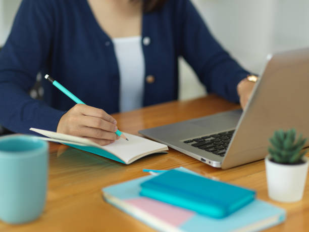 istock Close up view of female university student writing on blank notebook 1295727961