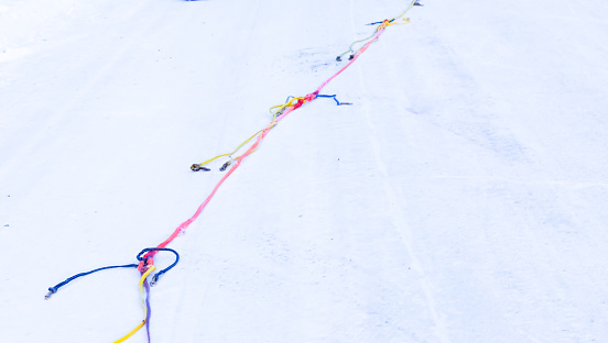 A leash is laid out across the snow in preparation for the sled dogs. Soon the dogs will be tethered together to form a team that will work together to race towards the finish line.