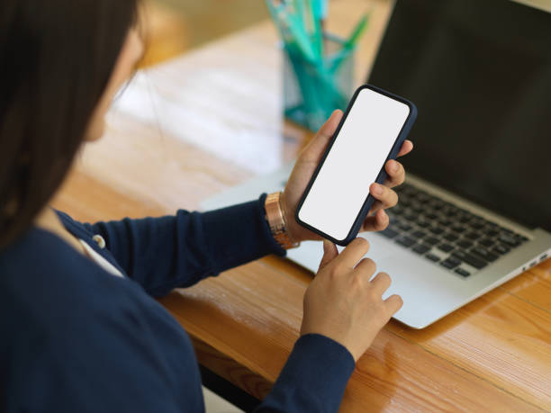 istock Businesswoman using smartphone while working with laptop 1295728363